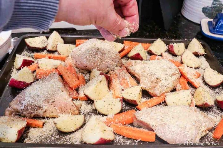 Sprinkling the chicken and veggies with breadcrumbs and Parmesan cheese.