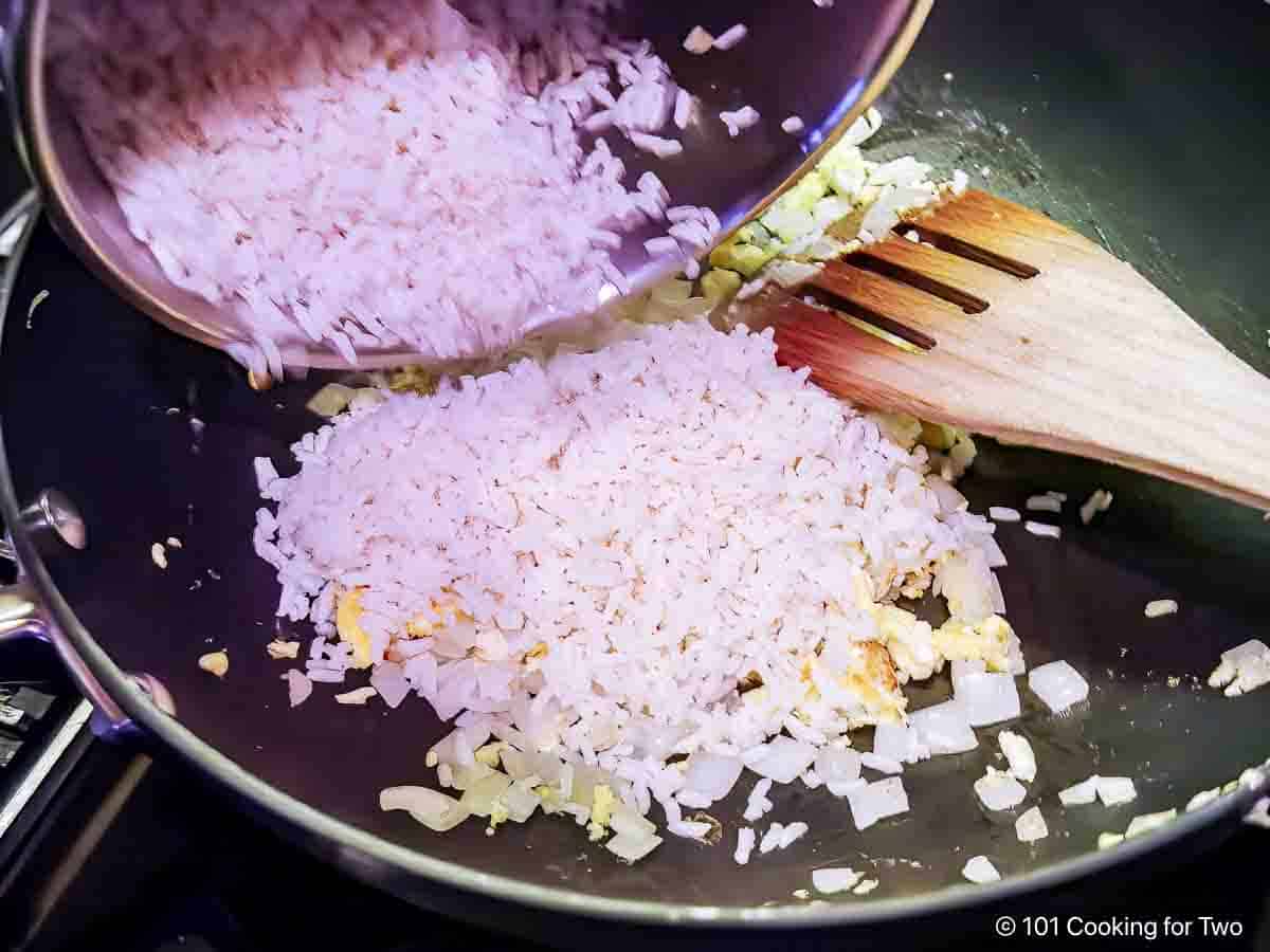 Adding the cooked rice to the fried egg.