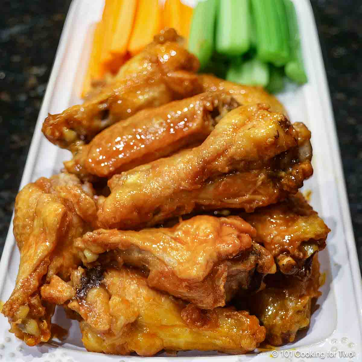 Baked chicken wings on a tray with veggies.