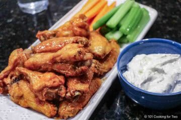 Baked chicken wings on a tray with veggies.l