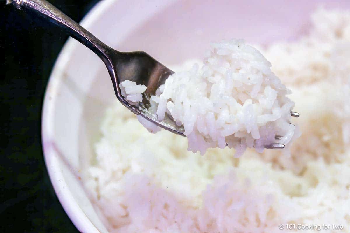 Cooked long-grain rice on a fork.