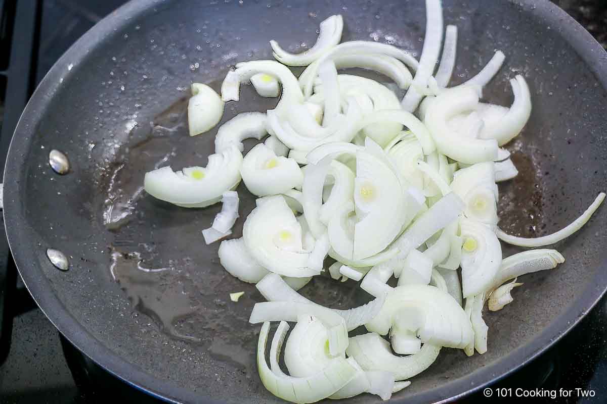 Cooking onion slices in fry pan.