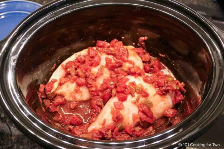 covering the chicken in the crock pot with the sauce,