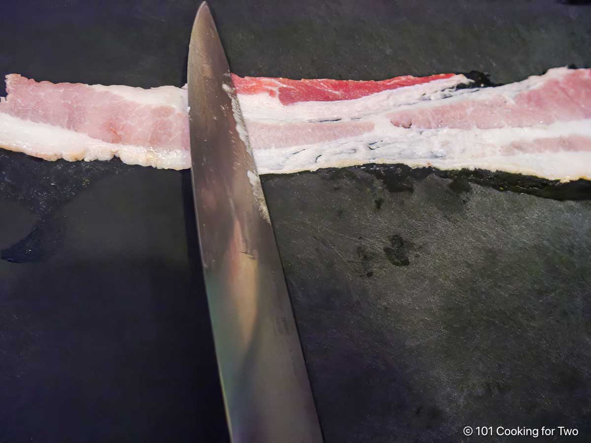 Flattening thicker bacon with the back of a knife.