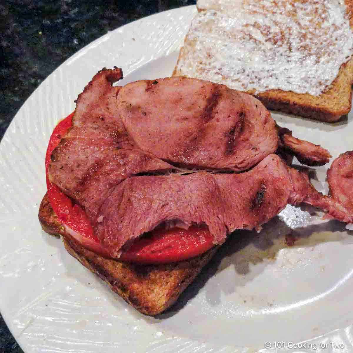 Glazed ham steak on a sandwich.