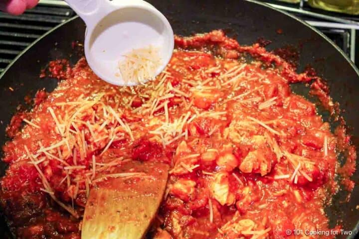 Mixing Parmesan cheese into the sauce.