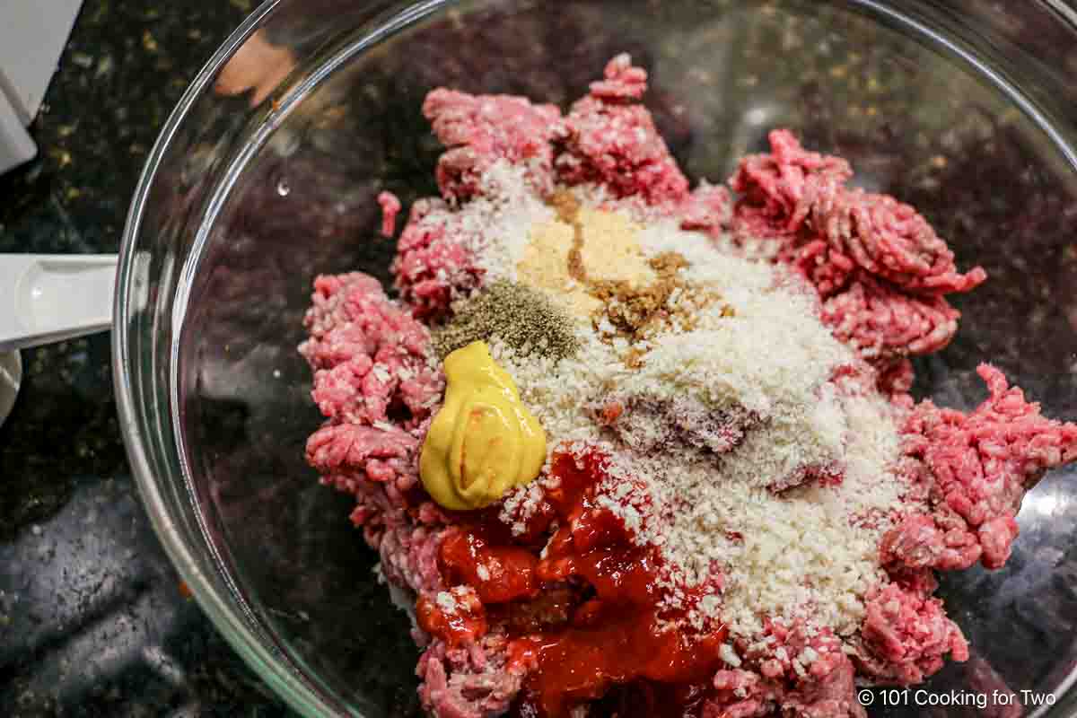 Mixing burger with bread crumbs and seasonings.