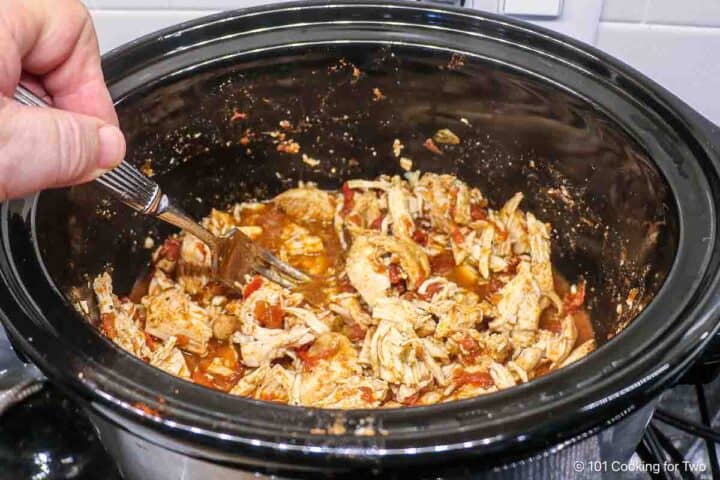 mixing shredded chicken back into the sauce.