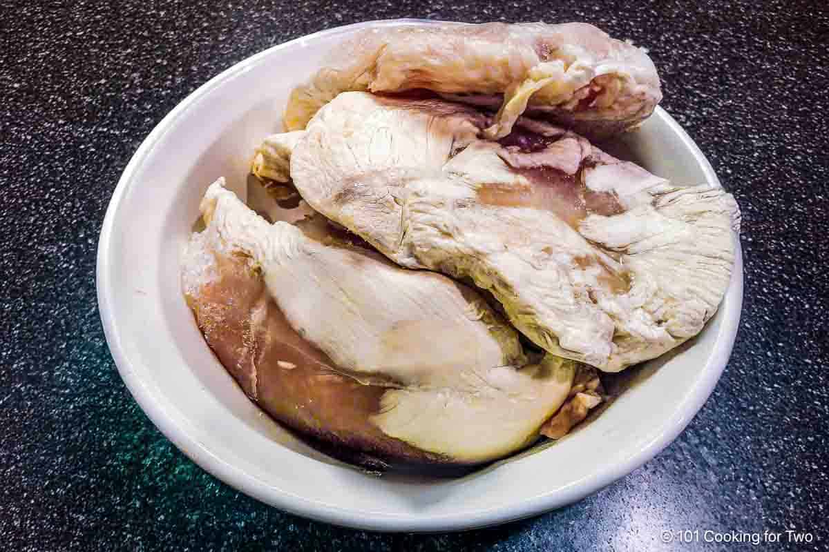 Pile of freezer-burnt chicken breasts on a white plate.