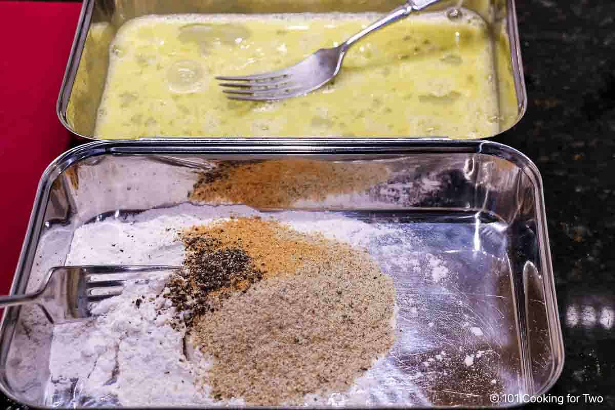 Preparing trays with wiped egg and breading ingredients.