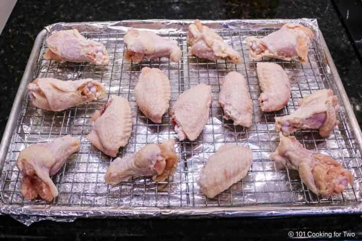 Raw chicken wings on a rack.