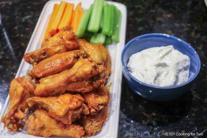 Serving blue cheese dip with crispy wings and veggies.