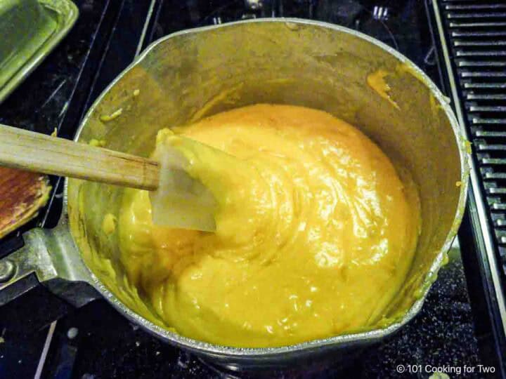 Mixing cheese into the roux thickened sauce.