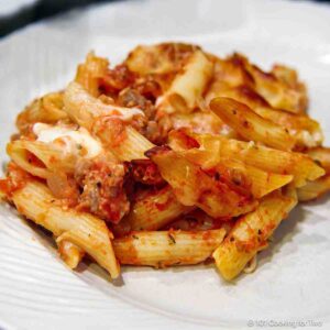 Pasta and sausage bake on a white plate.