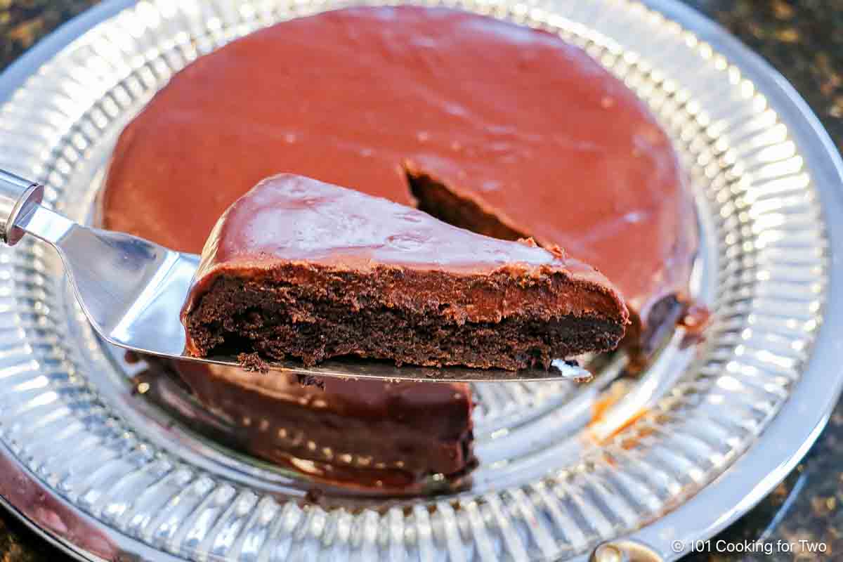 Slice of flourless chocolate ganache cake on a spatula full over the cake.