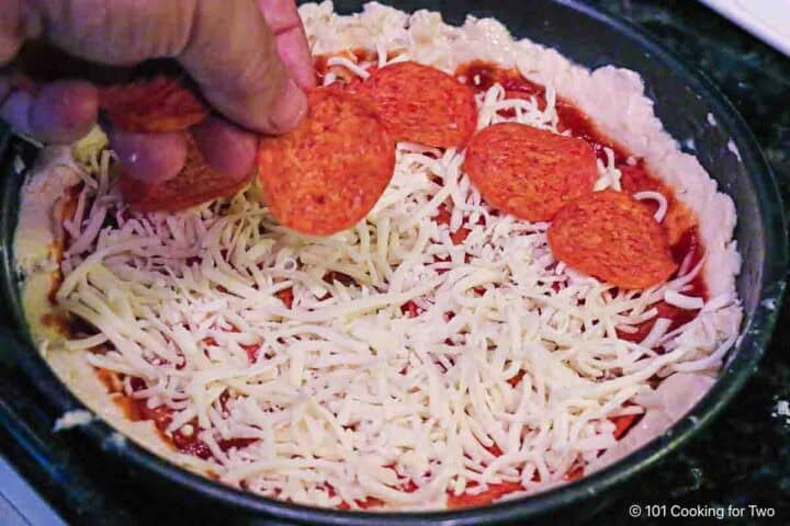 Adding toppings to the pizza.