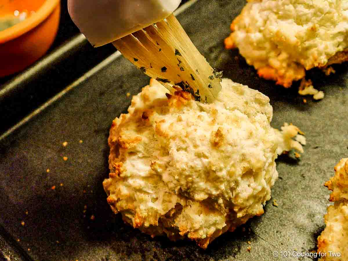 Brushing the biscuits with the butter mixture.