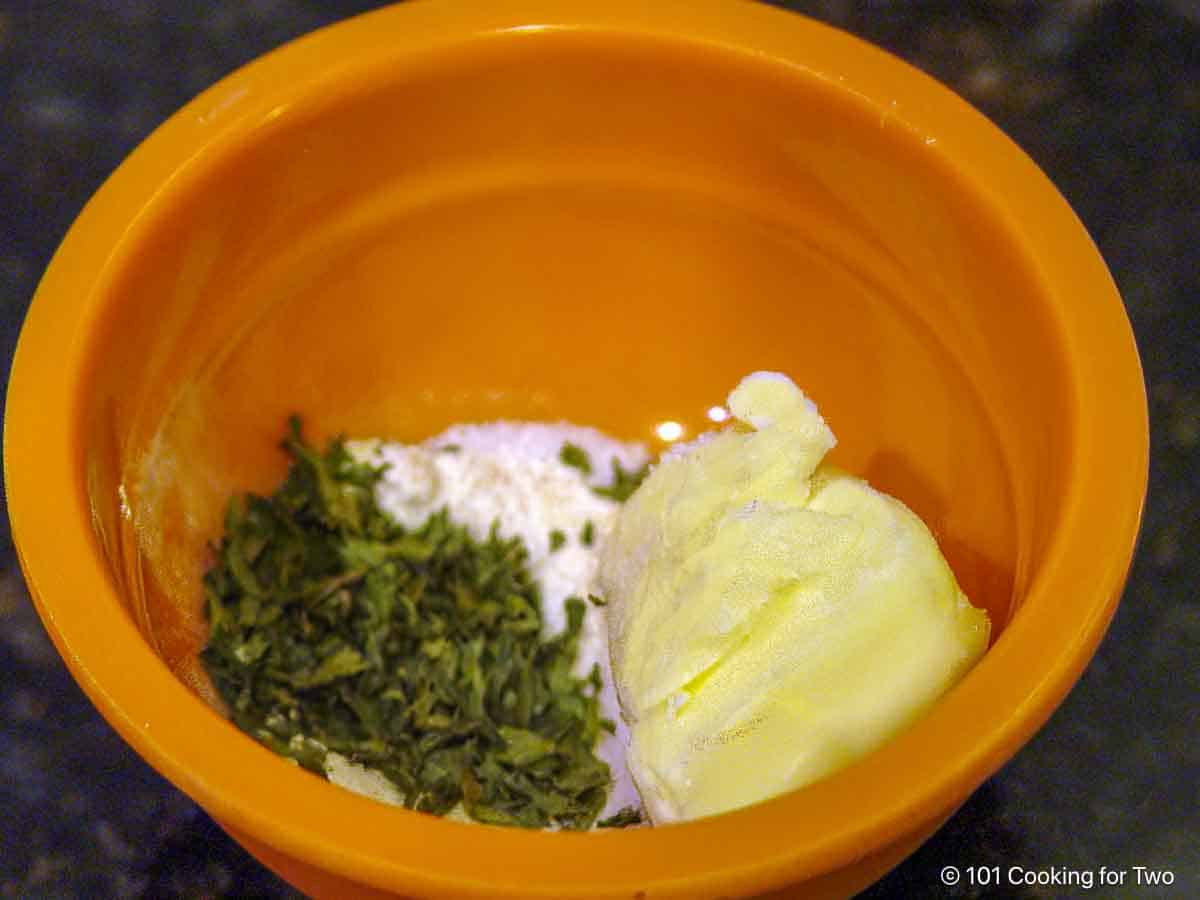 Butter with garlic powder and parsley in a small bowl.