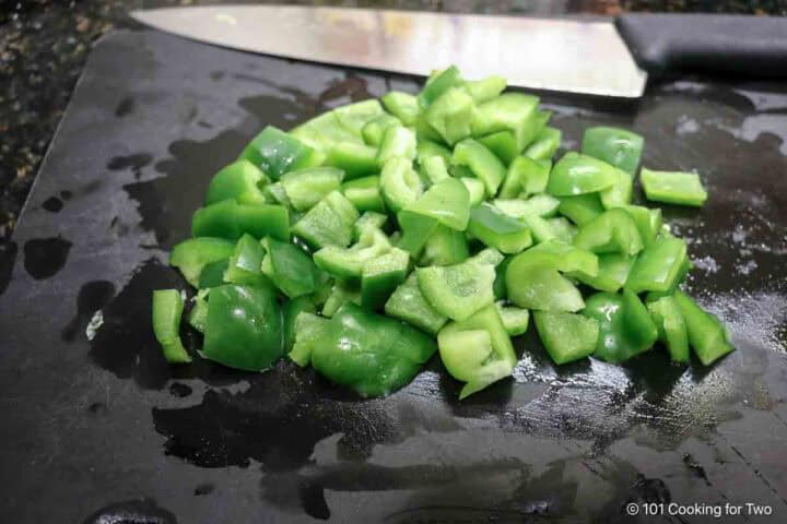 Chopped green peppers on a black board.