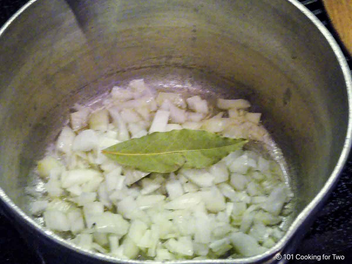 Cooking chopped onion with a bay leaf in butter.