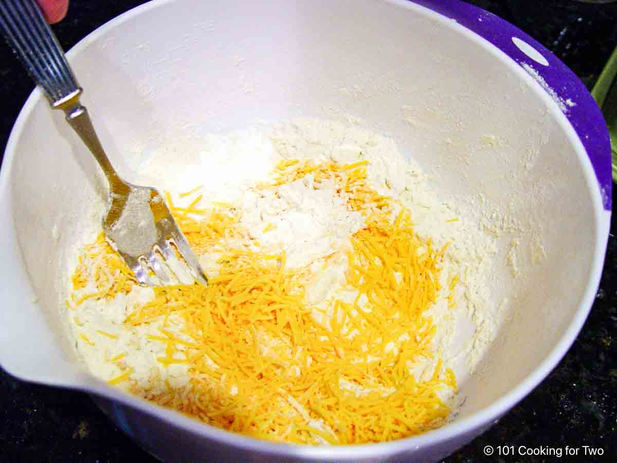 Mixing shredded cheese into the dough.