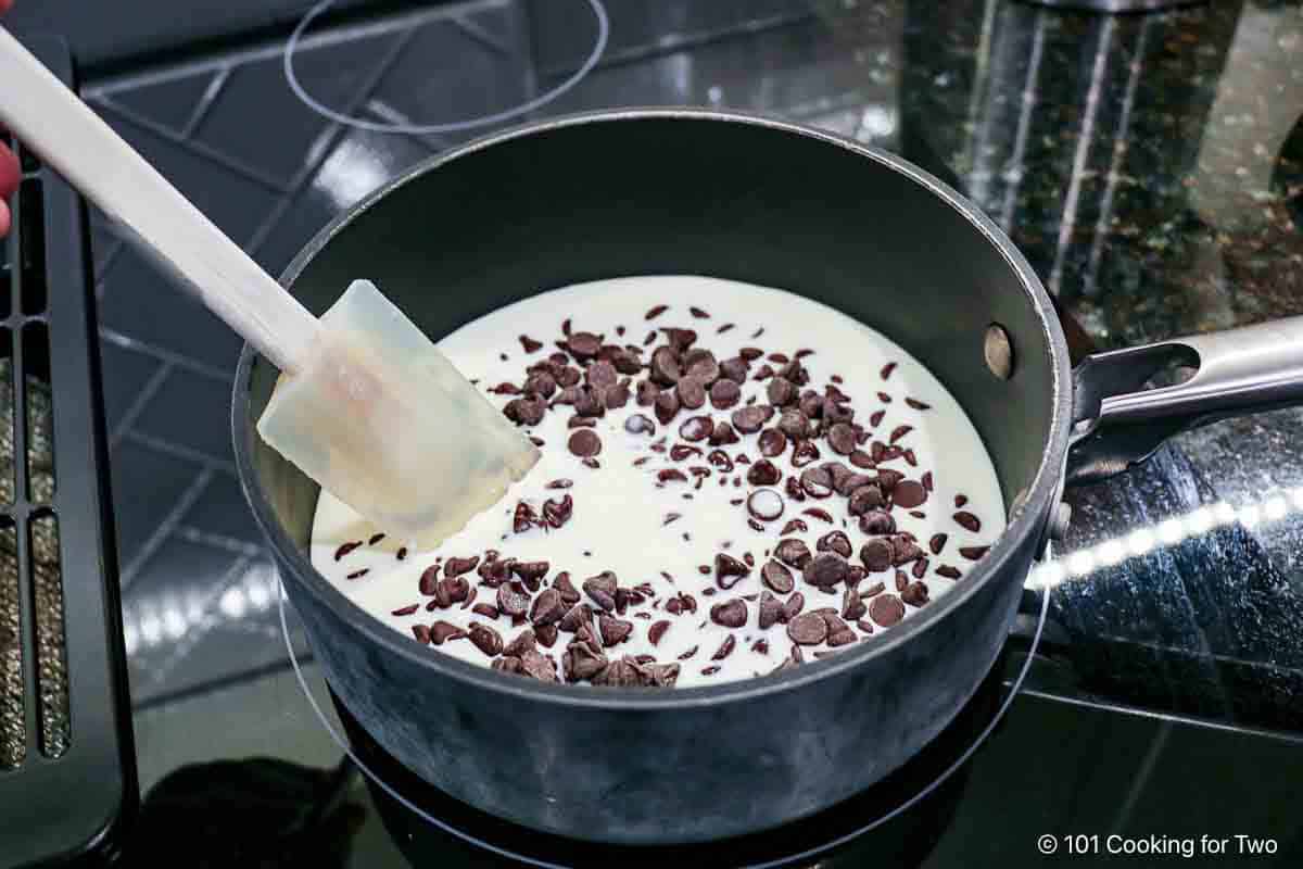 Mixing chocolate chips with cream in a sauce pan.