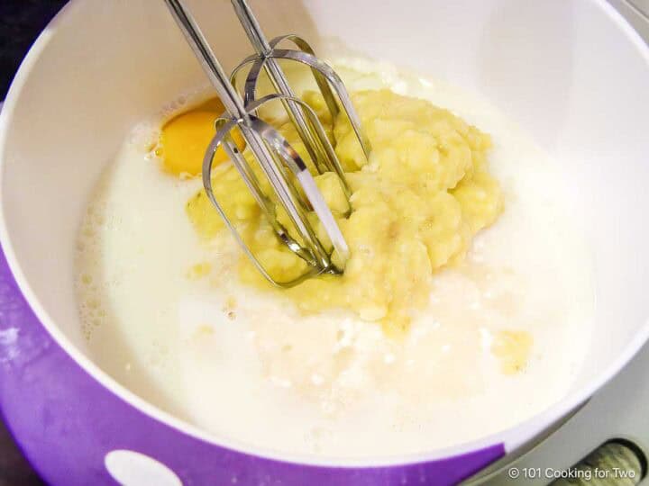 Mixing the bananas with other bread ingredients.