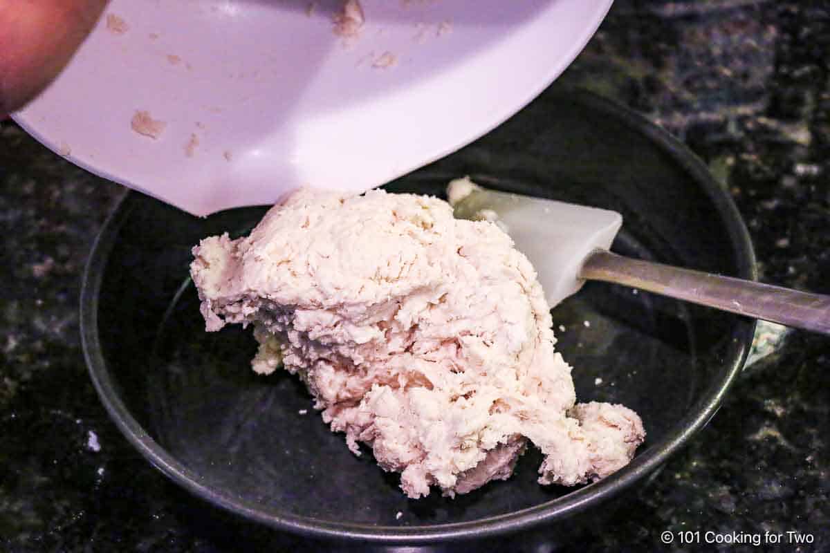 Pouring biscuit dough into prepared pan.