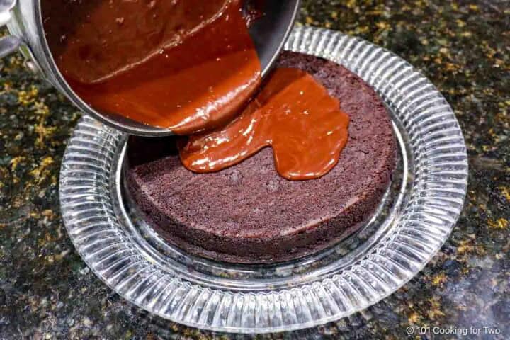 Pouring the chocolate ganache glaze onto the cake.