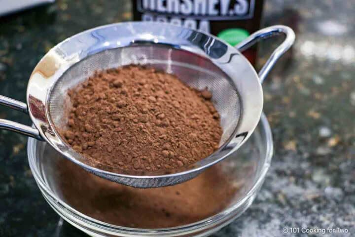 Shifting cocoa powder into a glass bowl.