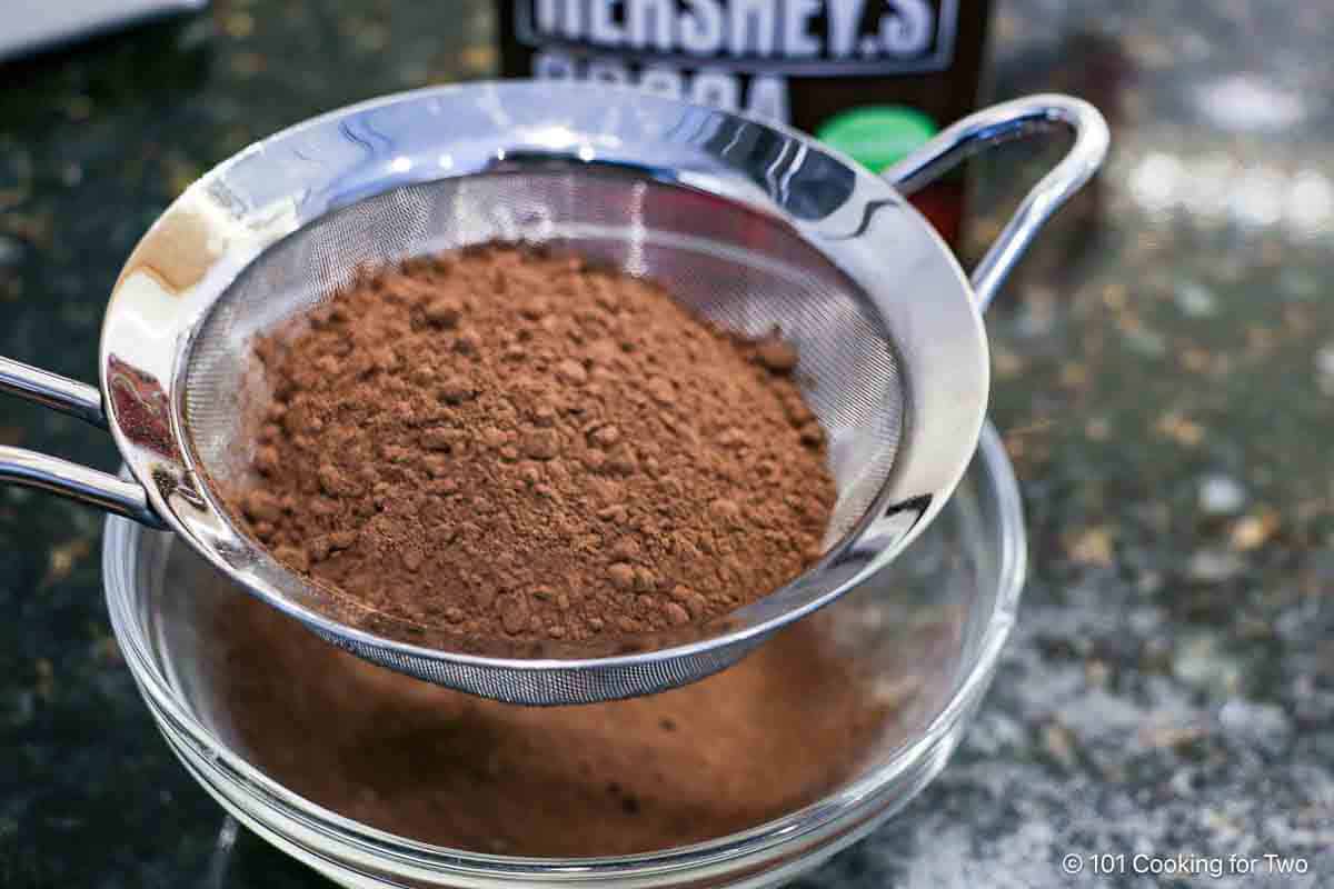 Shifting cocoa powder into a glass bowl.