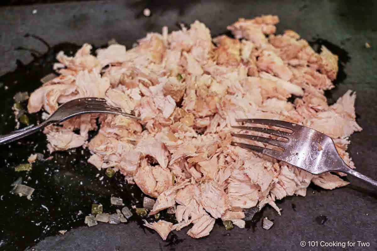 Shredding cooked chicken with forks.